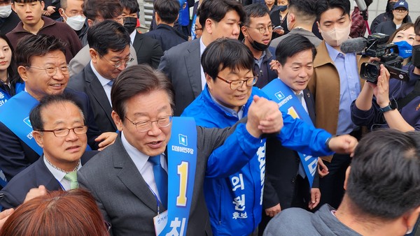 더불어 민주당 이재명 대표와 최덕종 후보가 필승을 다짐하며 주인들에게 인사를 건네고 있다