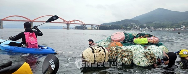 수중 정화활동에 참여한 거제해녀아카데미 소속 활동가(해녀)들이 태왁을 이용해 물속에서 수거한 쓰레기들을 육지로 끌고 나오고 있다(사진=환경재단)